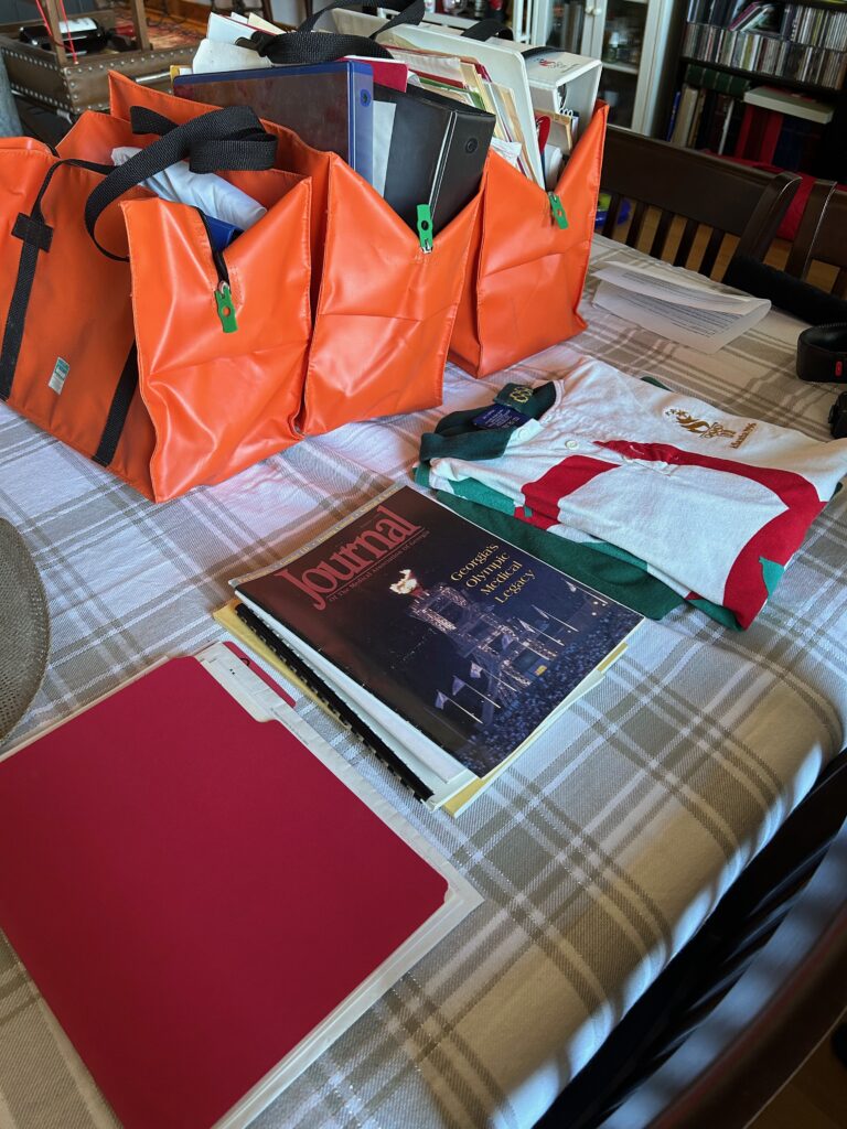 A table covered in orange bags, and piles of papers. 